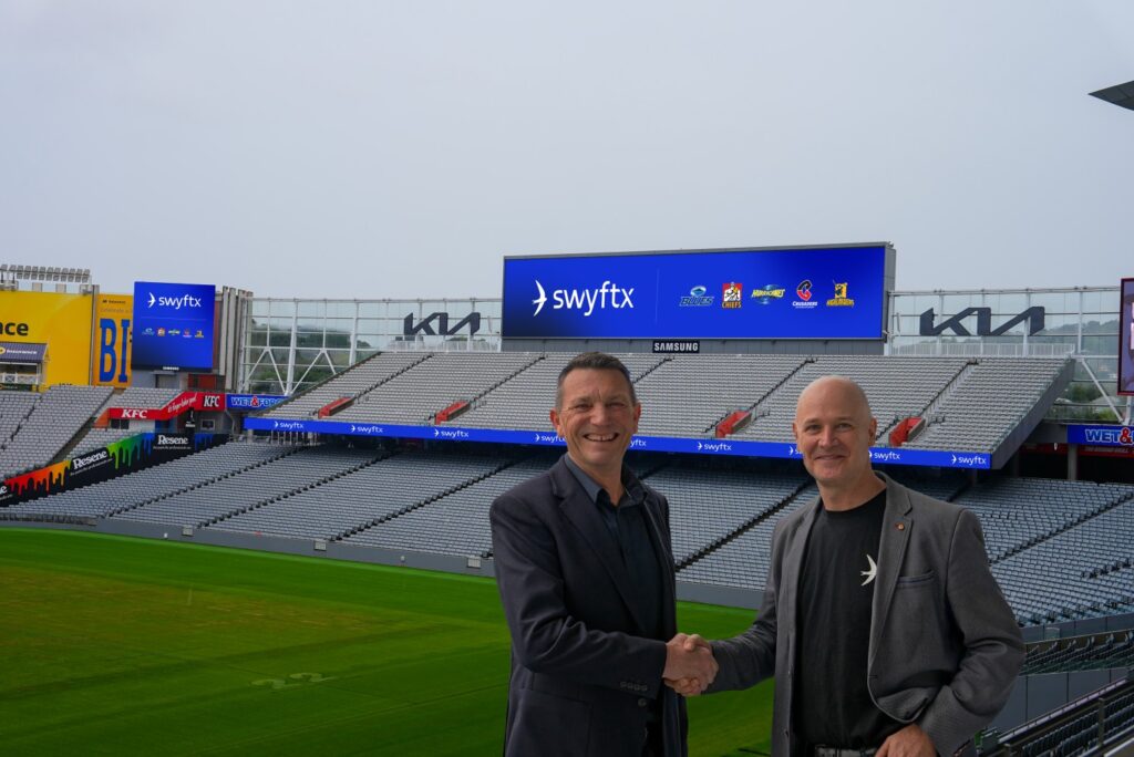 Swyftx representative with Super Rugby players at Eden Park announcing new sponsorship